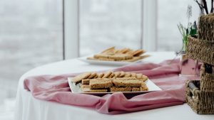Delicious breakfast served in square shaped plates on pink fabric on blurred background of window